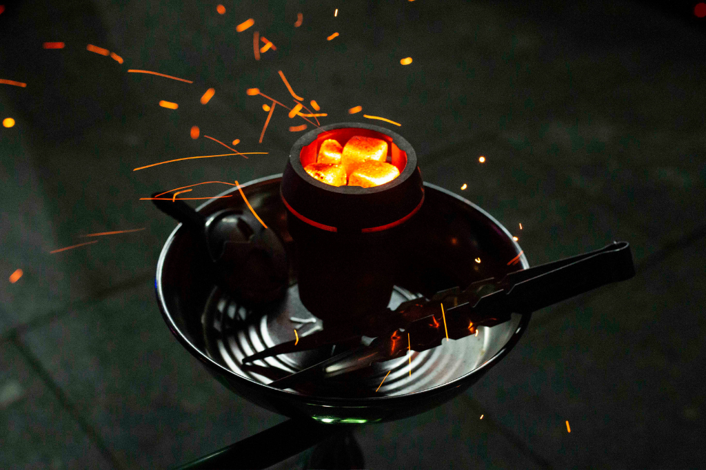 Red hot hookah coals on stovetop for perfect lighting.
