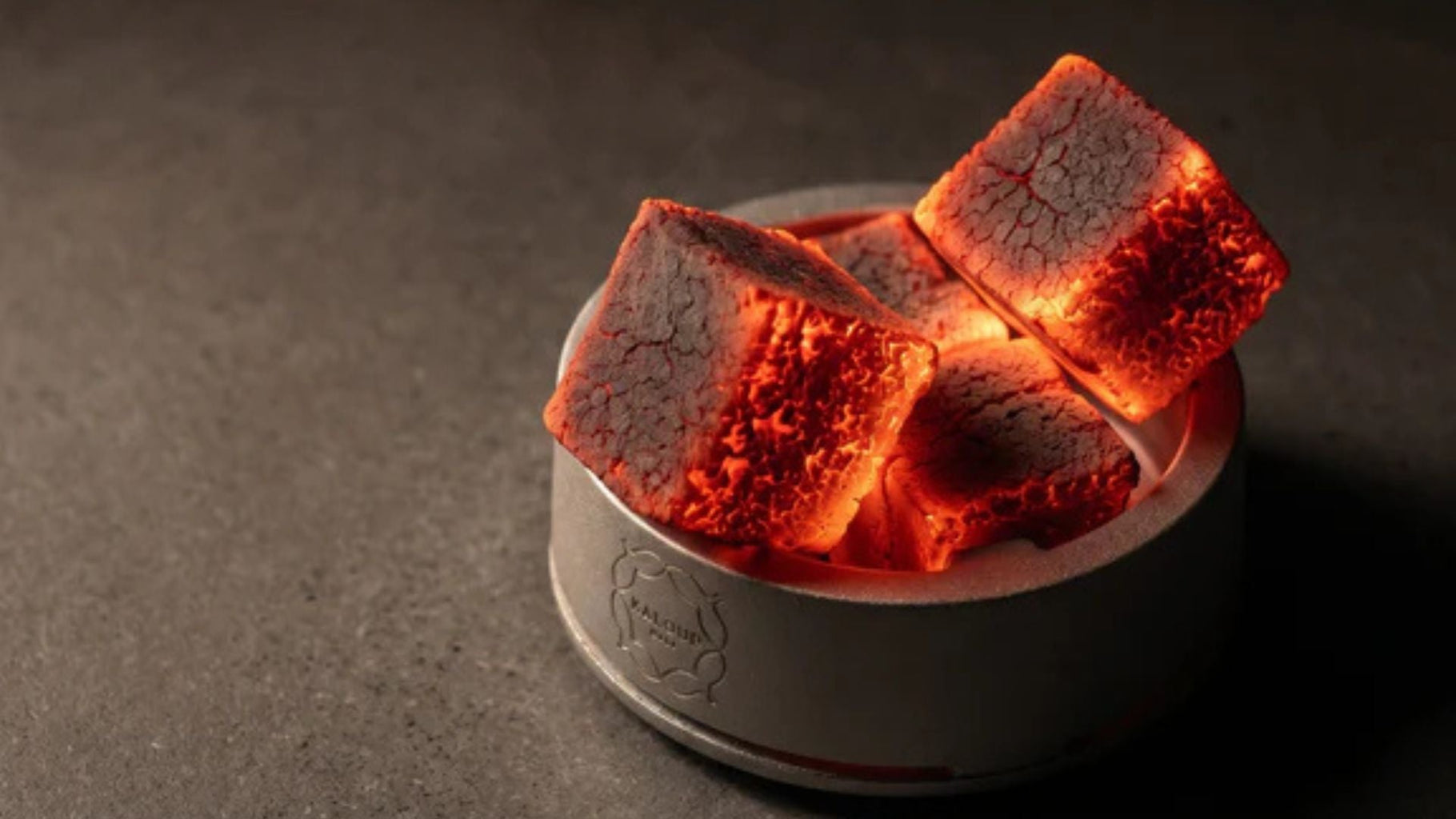 Heat management device containing four combusting charcoal cubes, distributing thermal energy through the conductive base