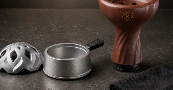Disassembled Kaloud Lotus HMD lid and base beside a brown Samsaris bowl, cleaning brush, and cloth, laid out on a dark stone surface
