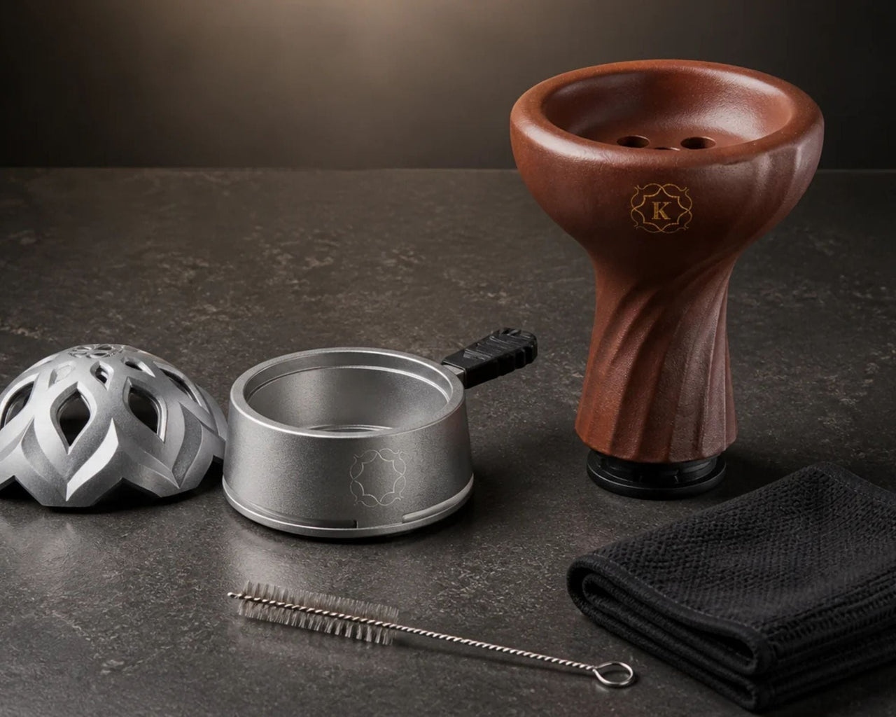 Disassembled Kaloud Lotus HMD lid and base beside a brown Samsaris bowl, cleaning brush, and cloth, laid out on a dark stone surface