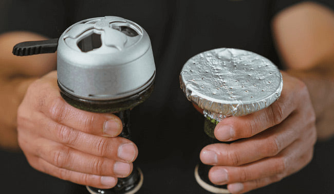 Heat management device positioned on bowl rim distributing charcoal thermal energy through vented base plate to tobacco layer below